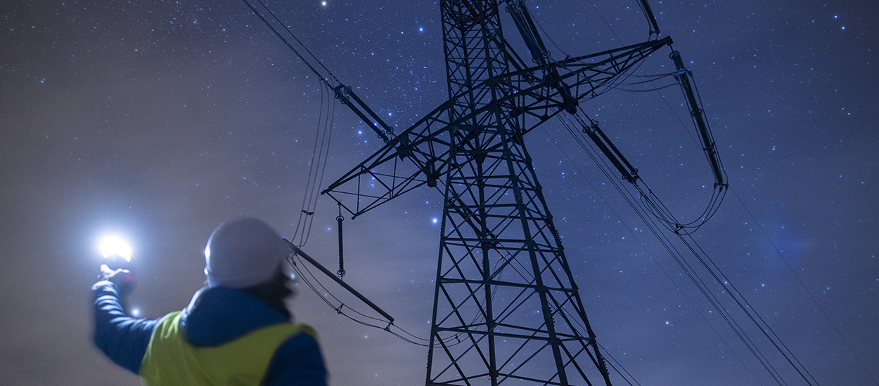 High voltage engineer working at night on the field. Sustainable energy.