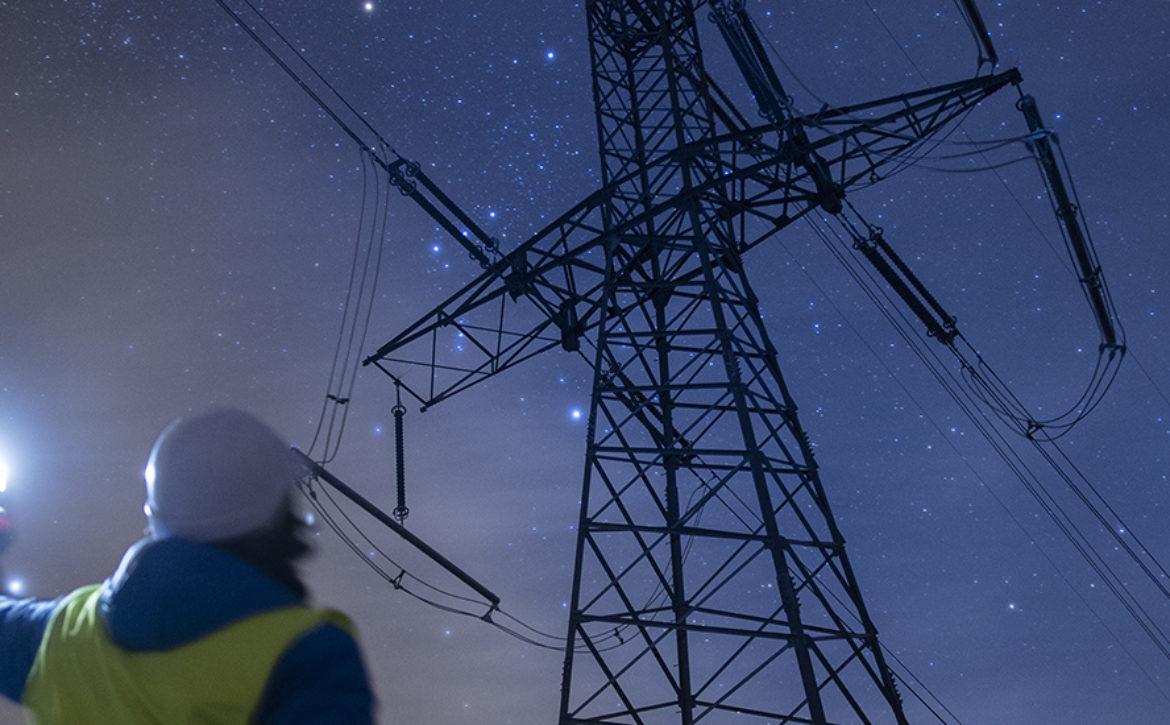 High voltage engineer working at night on the field. Sustainable energy.